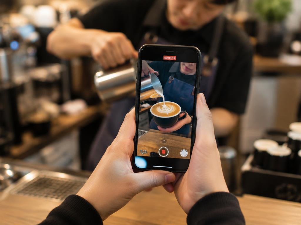 Phone recording a barista pouring latte art